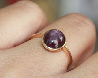 May include: A gold ring with a round, purple gemstone.