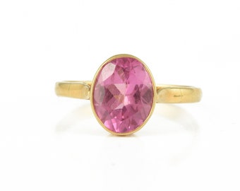 May include: A gold ring with a pink gemstone set in the center.