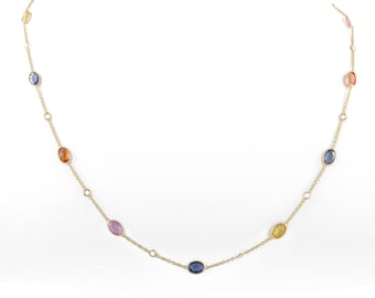 May include: A delicate gold necklace featuring oval-shaped gemstones in various colors, including blue, orange, pink, and yellow. The gemstones are evenly spaced along the fine gold chain, creating a colorful and elegant design. The necklace is displayed against a white background.