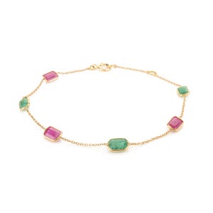 May include: A delicate gold bracelet featuring alternating rectangular gemstones. The bracelet showcases vibrant pink and green stones, connected by a fine gold chain. The clasp is also gold.