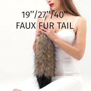 May include: A set of faux fur animal ears and a faux fur tail in shades of brown, tan, and black. The text 19"/27"/40" FAUX FUR TAIL is printed in black. The ears are pointed and fluffy, and the tail is thick with a dark black tip.