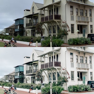 May include: Two rows of white houses with balconies and railings. The houses have a light blue trim and are surrounded by lush green trees and bushes.