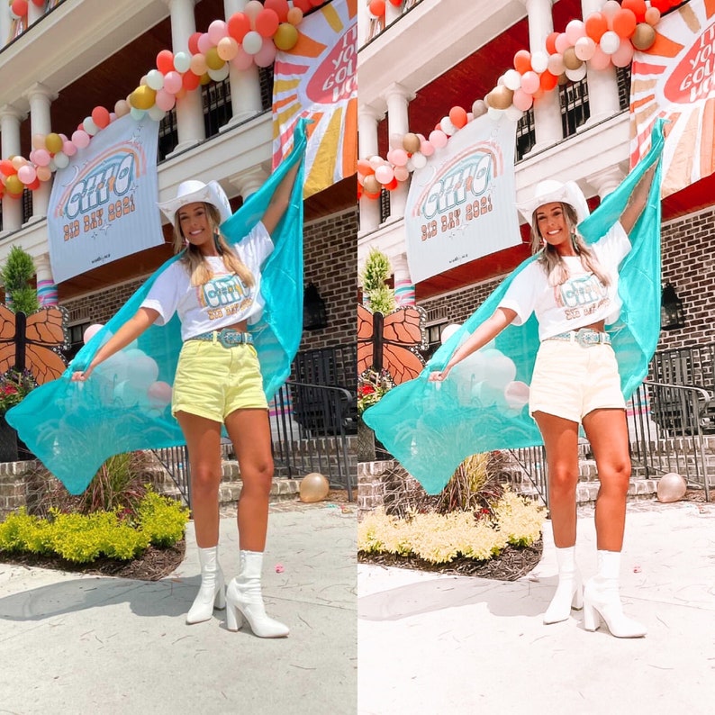 May include: A woman wearing a white t-shirt with the text "GTHO BIG DAY 2021" and a turquoise scarf, holding a blue and white scarf. She is wearing yellow denim shorts and white boots. The background is a building with balloons and a banner.