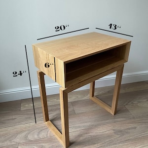 May include: A wooden end table with a shelf and a drawer. The table is 24 inches tall, 20 inches wide, and 13 inches deep. The shelf is 6 inches deep.