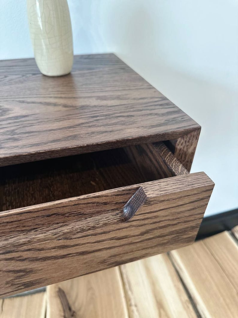 May include: A dark brown wooden wall-mounted bedside table with a single drawer. The drawer has a small wooden knob.