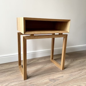 May include: A wooden side table with a shelf. The table is made of light brown wood and has a simple, modern design.