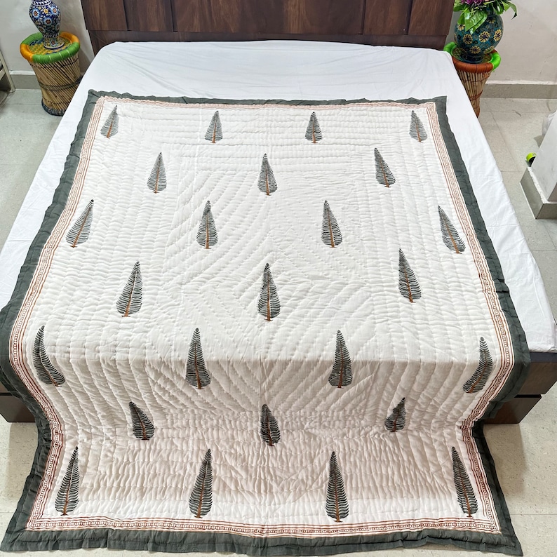 May include: White cotton quilt with a dark green leaf pattern. The quilt has a dark green border with a thin red stripe.