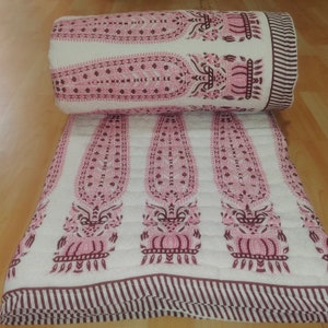May include: A white cotton quilt with a pink and brown paisley pattern. The quilt is folded in half and has a striped border.