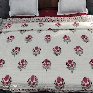 Può includere: Copriletto trapuntato bianco con un motivo ripetuto di disegni floreali rosa. Il copriletto ha un bordo decorativo ed è abbinato a cuscini bianchi. Il tema è biancheria da letto e arredamento per la casa.