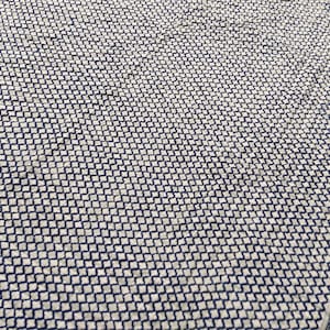 May include: A textile fabric featuring a repeating small-scale navy blue and white geometric quatrefoil pattern across the surface, with a distinct border design along the edge consisting of a thin striped band and a decorative floral motif.
