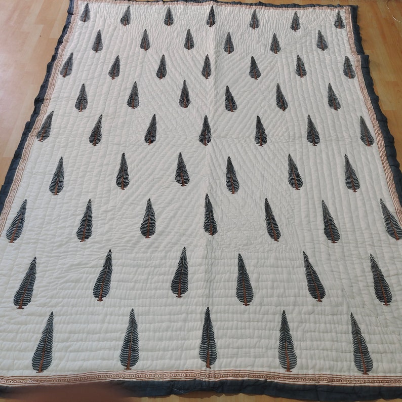 May include: White cotton quilt with a black leaf pattern. The quilt has a black border and a brown and orange trim.