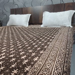 May include: A brown and white patterned bedspread with a floral design. The bedspread is made of cotton and has a quilted texture.