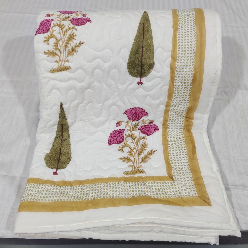 May include: White cotton quilt with a floral and leaf print in shades of pink, green, and gold. The quilt has a gold border with a repeating pattern.