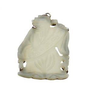 May include: A pale green jade pendant carved in the shape of a robed figure, possibly a deity or wise man. The figure holds a scroll and is suspended by a silver-colored bail. The pendant has intricate details and a smooth finish.