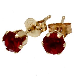 Peut inclure: Une paire de boucles d'oreilles à clous en or avec des pierres précieuses rondes, rouge foncé. Les boucles d'oreilles ont un design classique avec un sertissage à quatre griffes, mettant en valeur la couleur vibrante des pierres. Les tiges et les fermoirs sont également en or.