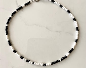 Könnte beinhalten: Eine schwarze und weiße Perlenkette mit einem silbernen Verschluss.