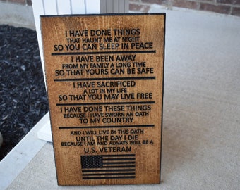 Op de afbeelding: Een houten bord met een patriottische boodschap over de offers die een Amerikaanse veteraan heeft gebracht. Het bord luidt: "Ik heb dingen gedaan die me 's nachts achtervolgen, zodat jij in vrede kunt slapen. Ik ben lange tijd van mijn familie weggeweest, zodat de jouwe veilig is. Ik heb veel geofferd in mijn leven, zodat jij vrij kunt leven. Ik heb deze dingen gedaan omdat ik een eed aan mijn land heb gezworen. En ik zal deze eed tot de dag van mijn dood nakomen, omdat ik een Amerikaanse veteraan ben en dat altijd zal blijven."