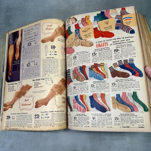 May include: A vintage advertisement for women's hosiery and ankle socks. The ad features a variety of styles and colors, including full-fashioned stockings, sheer stockings, and ankle socks with stripes and patterns. The text in the ad highlights the different features of each product, such as the 'full-fashioned' construction of the stockings and the 'sparkly' colors of the ankle socks.