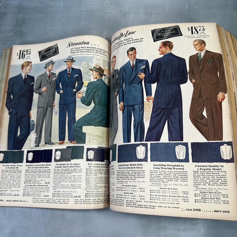 May include: A vintage magazine spread showcasing men's suits. The page features a variety of suits in different colors and styles, including a blue double-breasted suit, a brown suit, and a gray suit. The text on the page includes the names of the suits, their prices, and descriptions of their features. The magazine is from the 1940s.