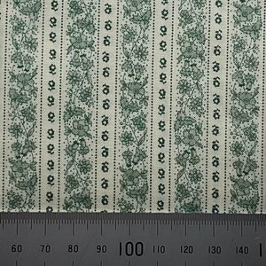 May include: A close-up of a white fabric with a repeating pattern of green floral stripes. A ruler is visible at the bottom of the image with markings from 60 to 140.