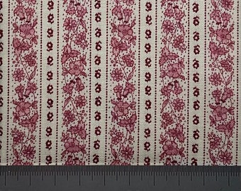 Puede incluir: Primer plano de una tela con un patrón floral repetitivo. El diseño presenta rayas verticales de flores rosas y líneas punteadas sobre un fondo crema. Una regla está en la parte inferior, mostrando medidas en centímetros.