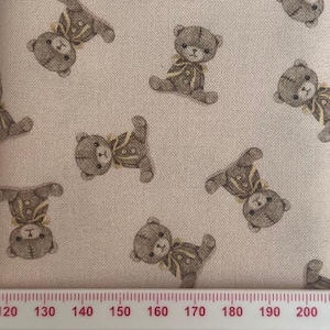 May include: Pale pink fabric featuring a repeating pattern of brown teddy bears dressed in yellow and brown outfits. The bears are in different poses, and the fabric has a textured finish.