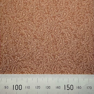 May include: Brown fabric with a white paisley pattern. A ruler is placed at the bottom of the image with the numbers 90, 100, 110, 120, 130, 140, 150, 160, and 170 visible.
