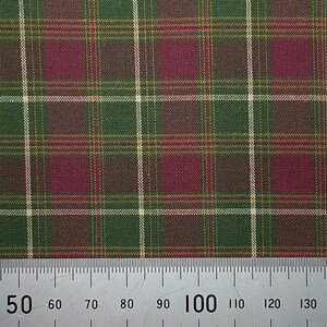 May include: A close-up of a green, brown and burgundy plaid fabric with a white ruler measuring 100 centimetres.