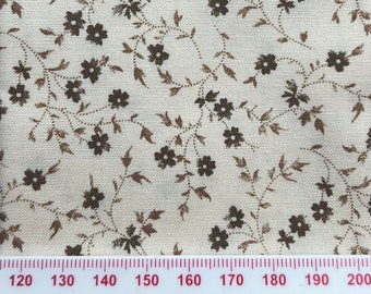 May include: A close-up of a white fabric with a brown floral pattern. The fabric has a subtle texture and the flowers are small and delicate.