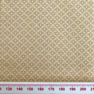 May include: Beige fabric with a white repeating pattern of small circles and crosses. The fabric is measured with a ruler in inches.