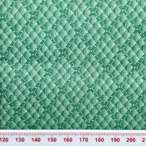 Peut inclure: Tissu vert avec un motif en losanges blancs. Le tissu est mesuré avec une règle en pouces.
