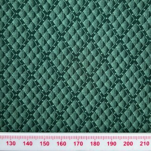 May include: Green fabric with a repeating geometric pattern of white triangles and diamonds. The fabric is measured with a ruler in centimetres.