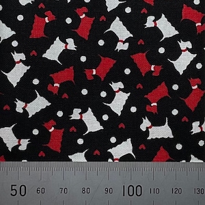 May include: Black fabric with a repeating pattern of white and red silhouettes of dogs. A ruler is placed at the bottom of the image with markings from 50 to 130.