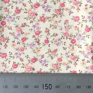 May include: Close-up of a white fabric with a pink and purple floral pattern. A ruler is placed at the bottom of the image with the number 150 marked.