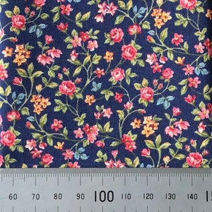 May include: A navy blue fabric with a small-scale floral print. The print features pink, yellow, and blue flowers on a dark blue background.