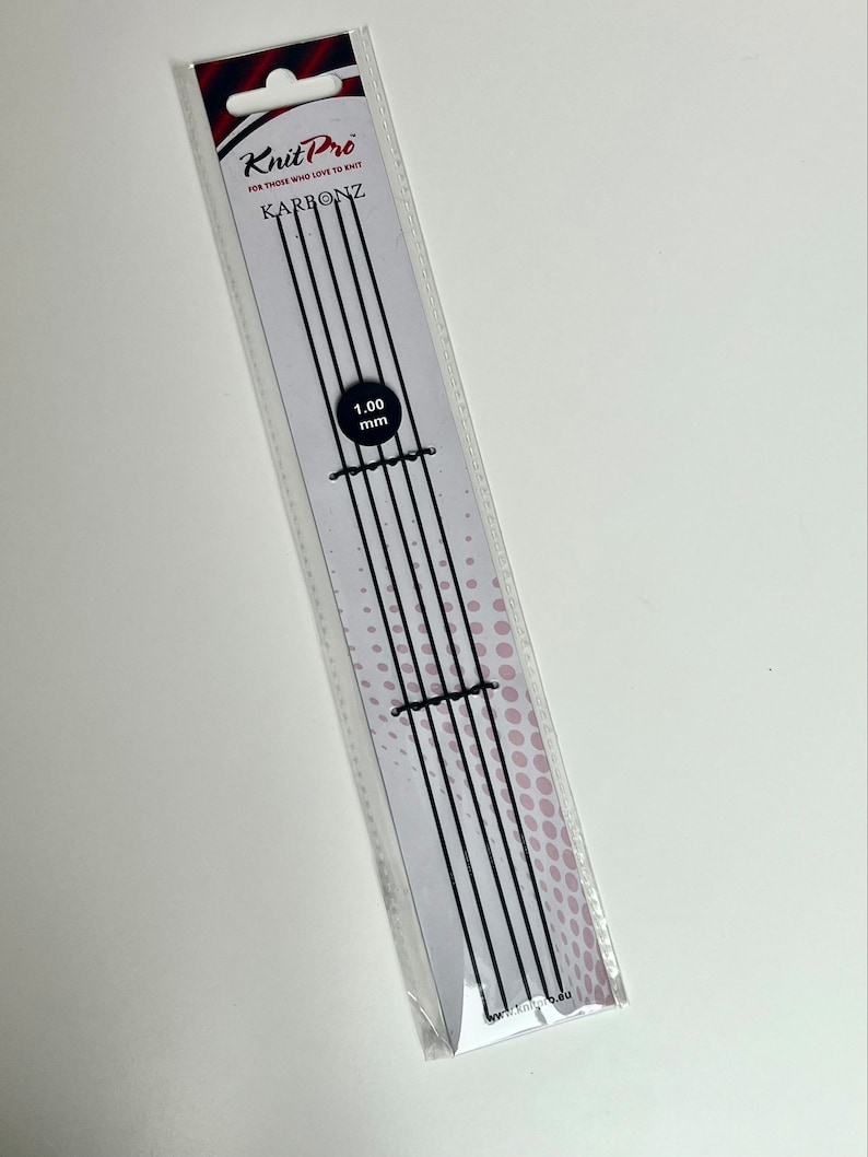 May include: Knit Pro Karbonz knitting needles, 1.00 mm, in a clear plastic package. The package has a white background with black vertical lines and the brand name in black and red. The needles are black.