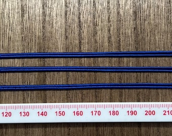 Op de afbeelding: Drie strengen donkerblauwe elastische koord, gemeten met een witte liniaal met rode markeringen. De liniaal toont metingen van 120 tot 210.