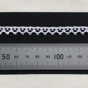 May include: White lace trim with a scalloped edge, measured against a ruler showing 150 centimetres.