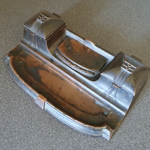 Op de afbeelding: Een antieke inktpot van koper en zilver met twee compartimenten en een reliëfdesign. De inktpot heeft een rechthoekige vorm met afgeronde hoeken en een decoratief ontwerp aan de voorkant.
