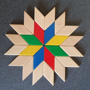 Könnte beinhalten: Ein sternförmiges Holzpuzzle mit rautenförmigen Teilen in Naturholz, Rot, Blau, Grün und Gelb. Das Puzzle liegt auf einer grauen Oberfläche und bildet ein farbenfrohes geometrisches Muster.