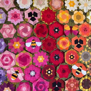 May include: A vibrant patchwork quilt with a floral design. The quilt features hexagonal blocks with flowers, bees, and star patterns in shades of pink, red, yellow, and purple. The quilt is a handmade textile.