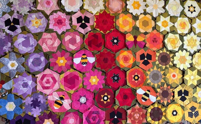May include: A vibrant patchwork quilt with a floral design. The quilt features hexagonal blocks with flowers, bees, and star patterns in shades of pink, red, yellow, and purple. The quilt is a handmade textile.