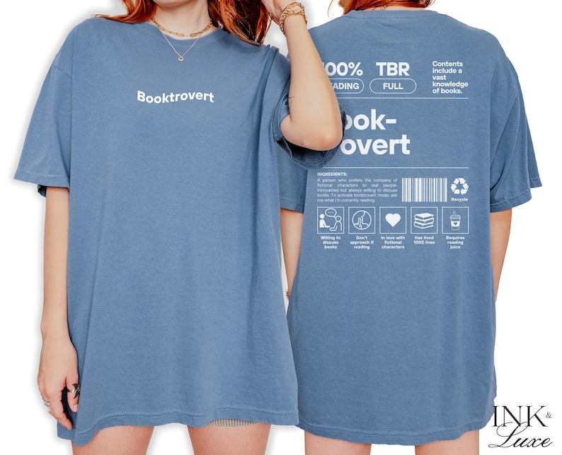 K&ouml;nnte beinhalten: Ein blaues T-Shirt mit dem Text "Booktrovert" auf der Vorderseite und "100% TBR, Reading Full, Book-overt" auf der R&uuml;ckseite. Die R&uuml;ckseite enth&auml;lt auch eine Liste von Zutaten, um ein Booktrovert zu sein, darunter "bereit, B&uuml;cher zu entdecken", "erwarte kein schnelles Lesen", "verliebt in fiktive Charaktere", "habe &uuml;ber 1000 B&uuml;cher geliebt" und "ben&ouml;tigt Lesesaft".