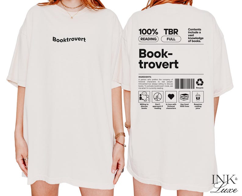 K&ouml;nnte beinhalten: Wei&szlig;es Oversize-T-Shirt mit dem Text "Booktrovert" auf der Vorderseite und einer Grafik auf der R&uuml;ckseite, die "100% TBR Reading Full" und "Book-trovert" mit einer Liste der Zutaten f&uuml;r einen Booktrovert sagt.