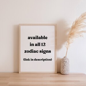 May include: A framed print with the text "available in all 12 zodiac signs" on a white background. The print is displayed on a wooden surface, with a vase of pampas grass to the right. The Ink + Luxe logo is in the bottom left corner.