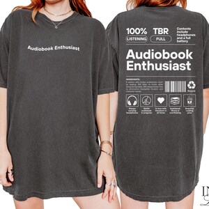 May include: Black oversized t-shirt with white text that reads "Audiobook Enthusiast" on the front and "100% TBR (LISTENING FULL) Audiobook Enthusiast" on the back. The back text also includes a list of features and a barcode.