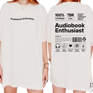 May include: White t-shirt with the text "Audiobook Enthusiast" printed on the front. The back of the shirt has the text "100% Listening TBR Full" and "Audiobook Enthusiast" with a list of ingredients for an audiobook enthusiast.