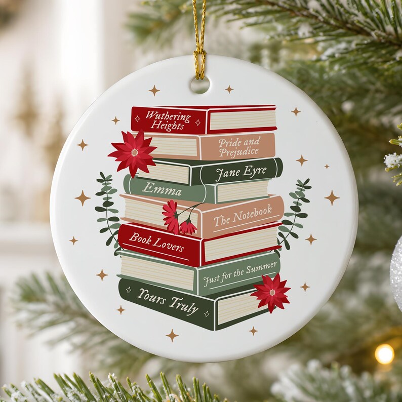 May include: A round white ceramic ornament with a gold hanging string featuring a stack of illustrated books titled Wuthering Heights, Pride and Prejudice, Jane Eyre, Emma, The Notebook, Book Lovers, Just for the Summer, and Yours Truly.