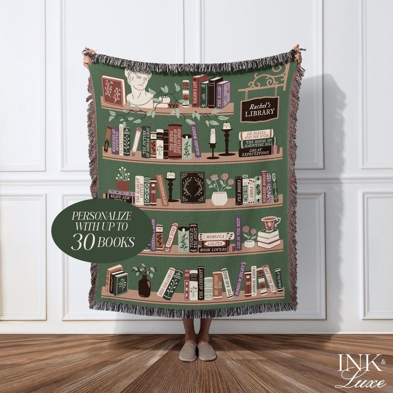 May include: A green woven throw blanket with a bookshelf design featuring a variety of books, plants, and candles. The blanket is personalized with the text "Rachel's Library" and has a label that says "Personalize with up to 30 books".