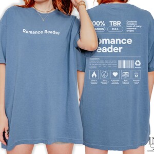 May include: A blue t-shirt with the text "Romance Reader" on the front and a list of romance tropes on the back. The shirt is made of a soft, comfortable material and is perfect for everyday wear.